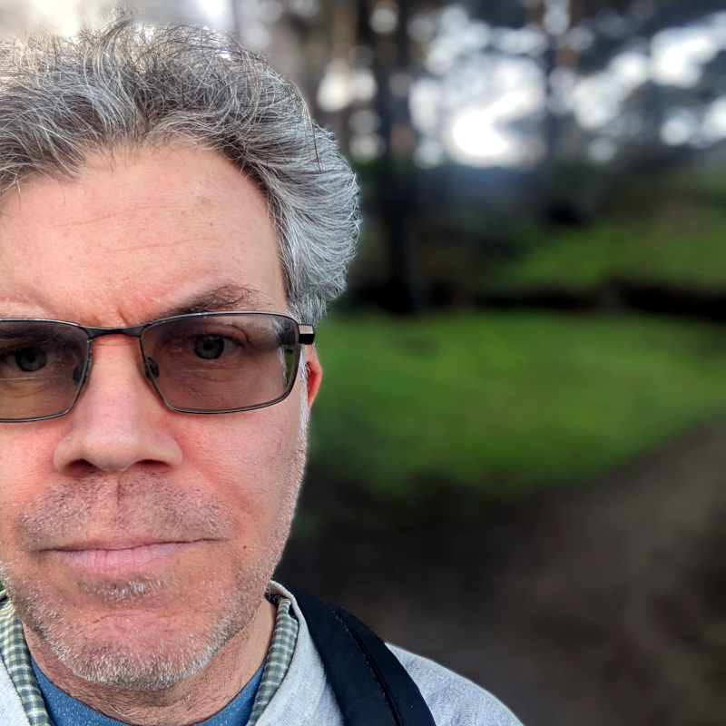[photo: Author selfie with green hillside in background]