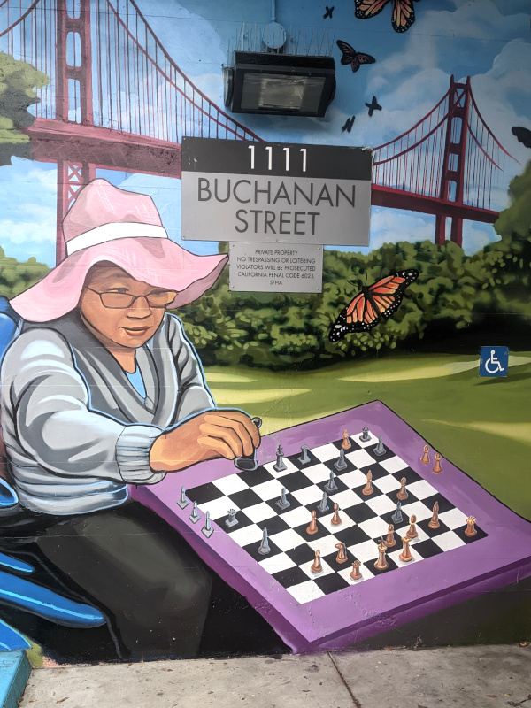 [mural at 1111 Buchanan St. A lady sits across the chessboard from you. She's playing black, you're white]