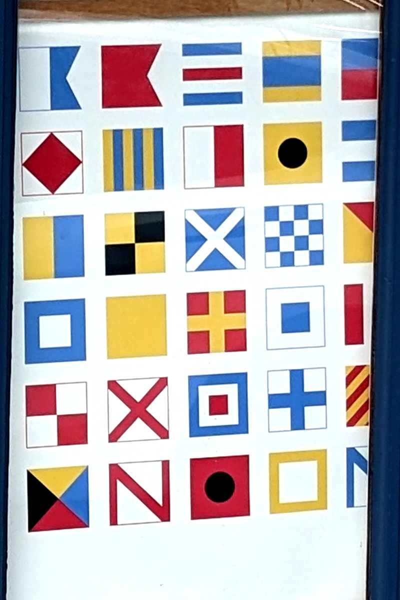 sign featuring mostly maritime signal flags but the last row is weird