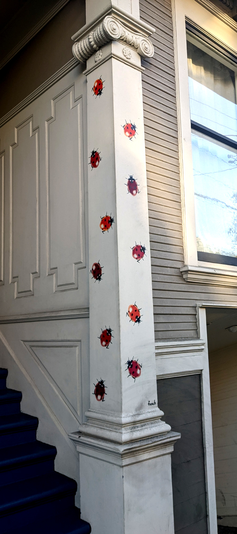 [photo: building column decorated with painted-on ladybugs]
