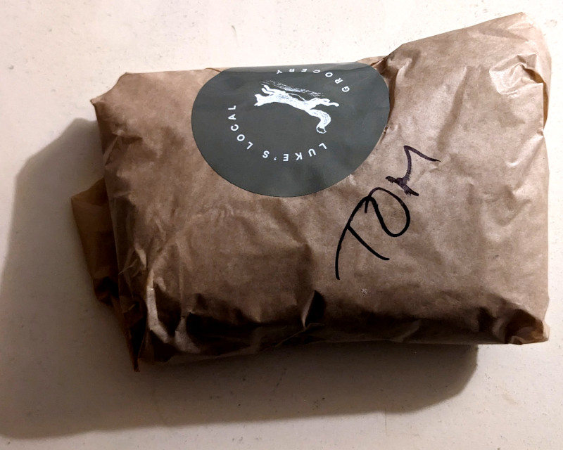 wrapped-up sandwich; the wrapper is labeled "Tom"