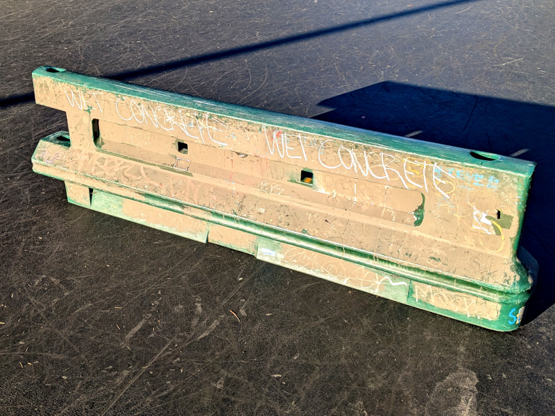 gray plastic traffic barrier with "wet concrete" written on it in a couple of places