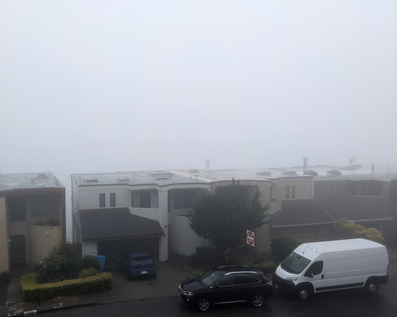 in the foreground: some houses, somewhat grayed out by fog. in the background: just a gray wall of fog