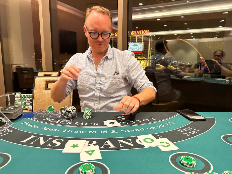 nerdy-looking David Hill is dealing blackjack, but the cards are weird: one has just a big star on it. Another, a triangle surrounding a star. Another has an arrow in a circle? Weeeeird