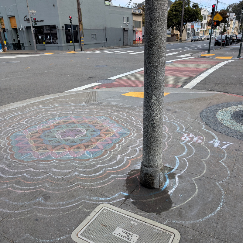 sidewalk chalk art: hexagon filled with a grid of triangles constructed from circular arcs rendered in colored chalk with a gradient heading out from the center. Tucked in the corner: "8647"
