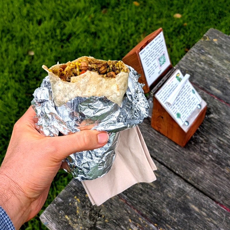 little wooden box atop a picnic table. also a half-eaten burrito