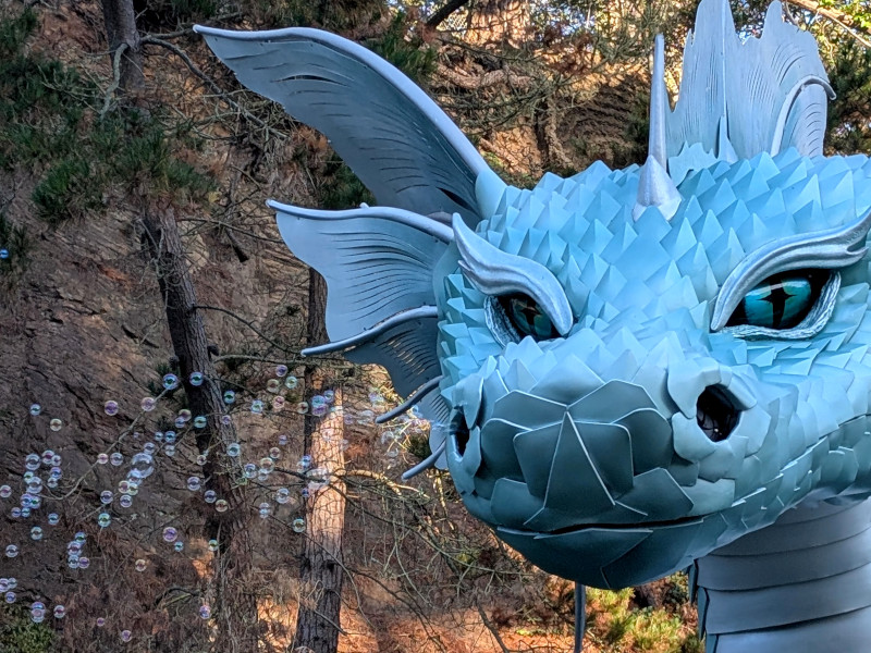 head of a metal(?) statue of a sea serpent blows soap bubbles from a nostril
