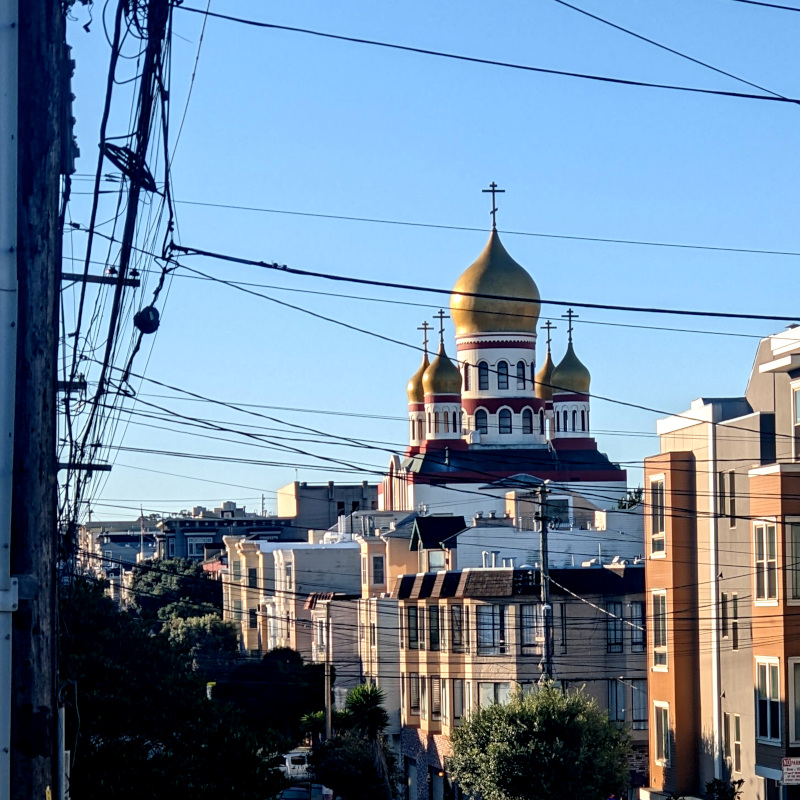 hilly residential street, but in the background there is a big cathedral topped with five big golden onion domes