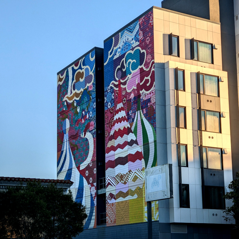 big mural on the side of a big building, 4200 Geary Blvd. There are Russian-looking swirly-painted onion domes. There are also Chinese-looking painting-ish clouds and a dragon