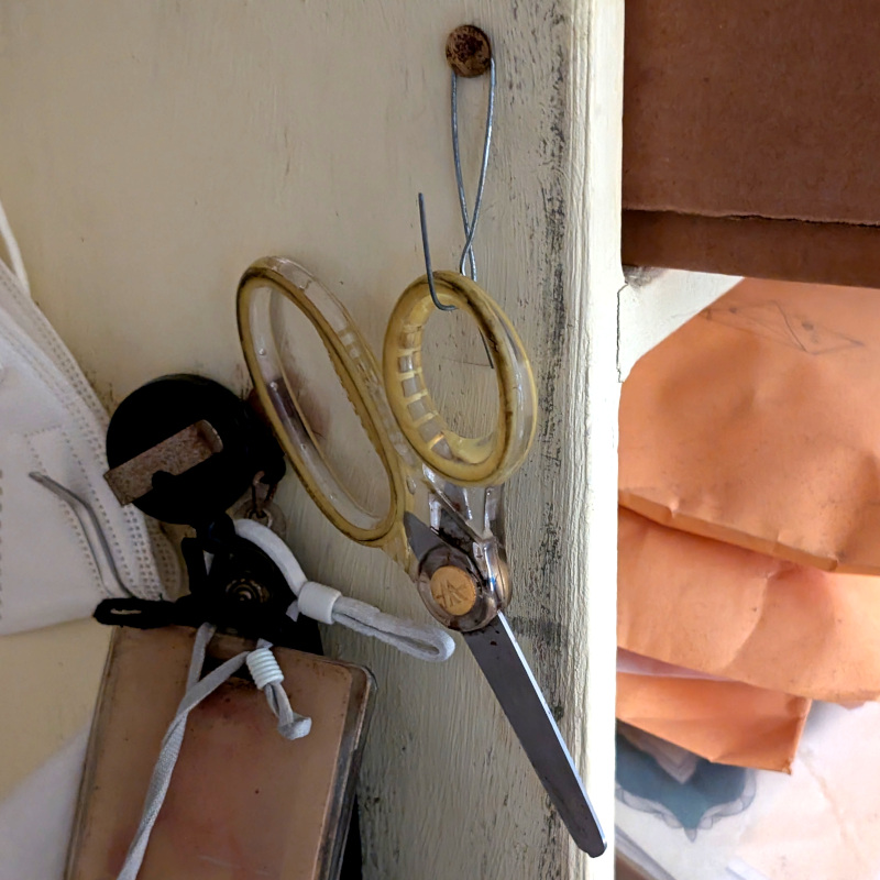 pair of safety scissors hanging from a hook on the side of a bookshelf