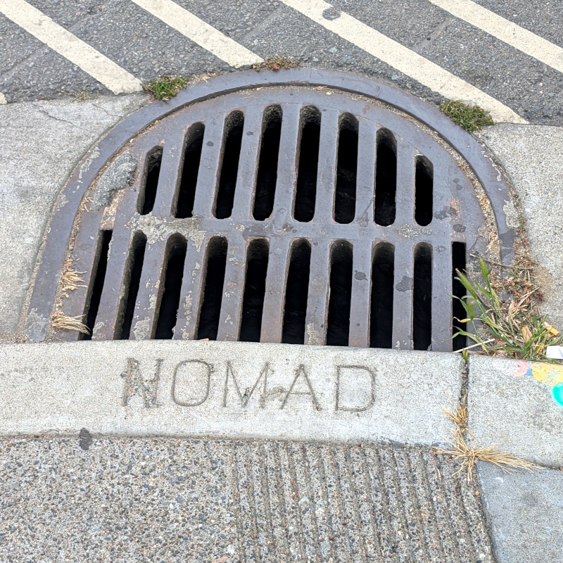sidewalk curb with a "Nomad" carved in it where you might expect a street name e.g., Irving