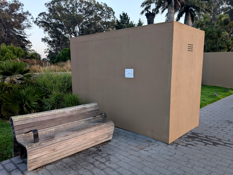 big box looms over a modern-art-ish bench on a sidewalk