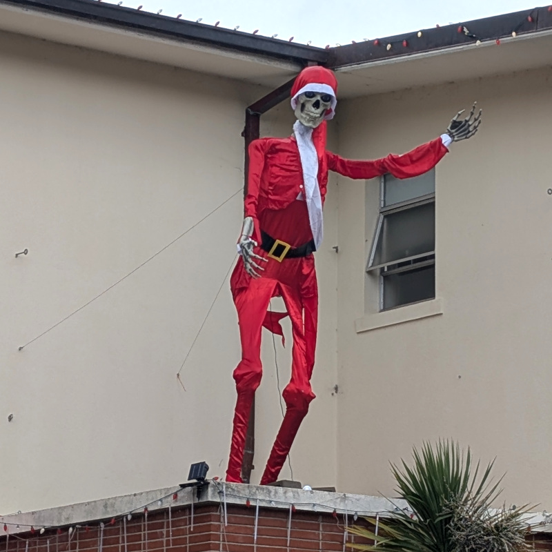 Giant skeleton in a giant red Santa suit hails the viewer