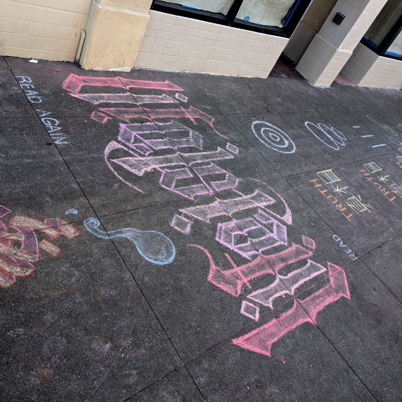 sidewalk chalk art: an ambigram that says "Life Islam" whether read right-side-up or rotated 180°