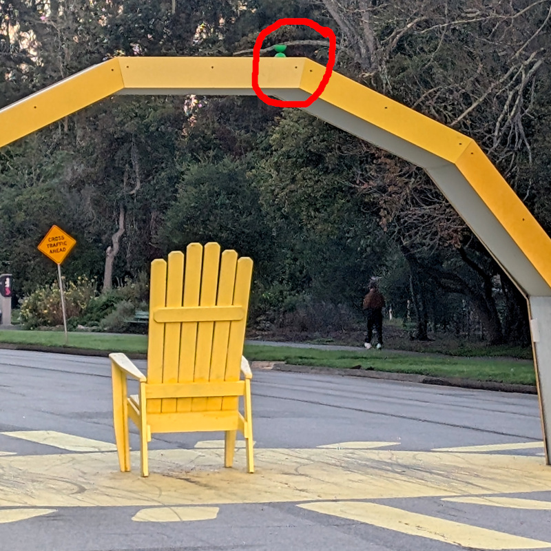 altered photo: that fnnch art installation Solar Arch, still with a yo-yo, ahem, I mean diabolo on top. the photo has been edited, adding a hand-drawn red circle to point out the little green diabolo