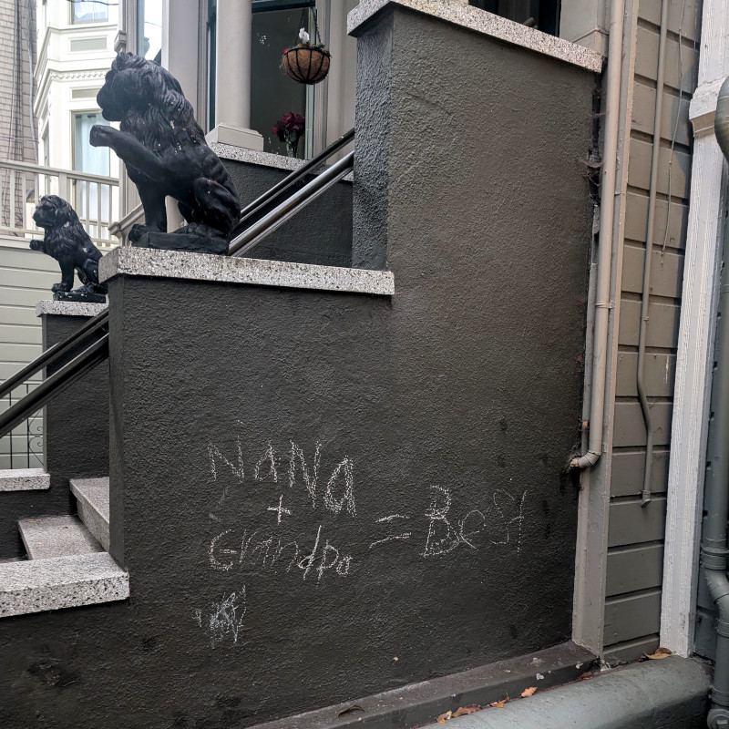 wall in front of house. There's some text in a child's scrawl, probably written in chalk: Nana + Grandpa = Best