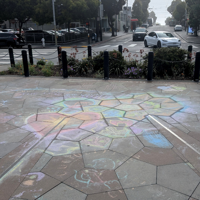 sidewalk chalk art: colorful design. Kinda difficult to pick out elements to describe; it's pretty scuffed. Part of it is definitely a heart?