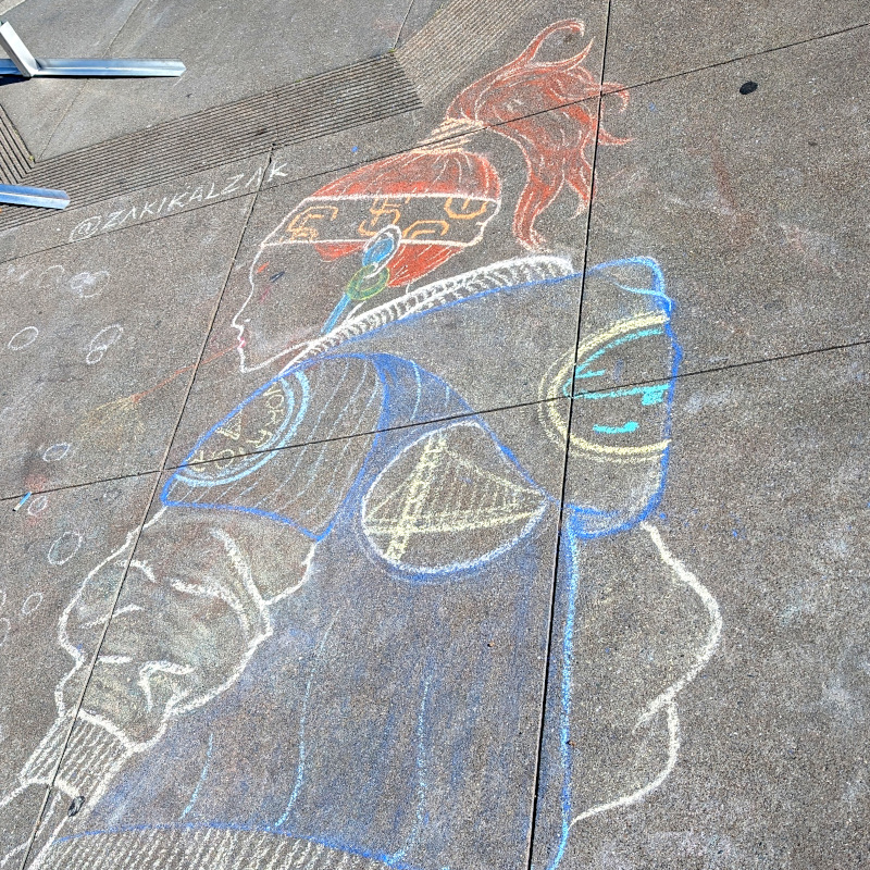 sidewalk chalk art: bicyclist sits wears a jacket with a GSW logo