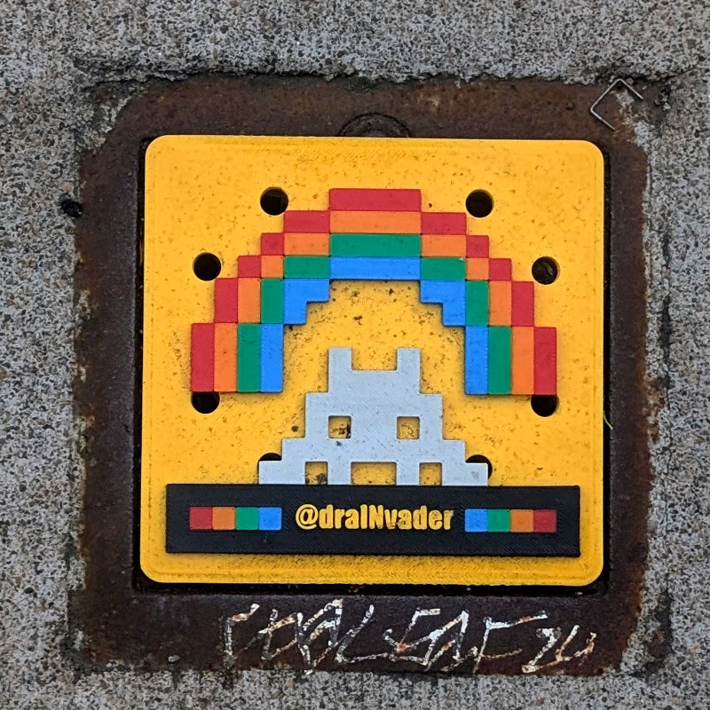 sewer drain cover made of 3D-printed plastic. bright yellow background. pixel art with Space Invader under a rainbow over spectrum-colored dots by signature draINvader