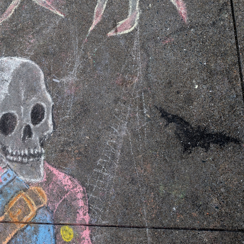 sidewalk chalk art: zooming in next to the ghost heads to notice something subtle: there are faint spiderwebs drawn here