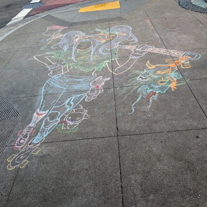 sidewalk chalk art: demon hunter on a roller skates. Her t-shirt proudly bears the logo of Lucca Deli. She carries a long-handled battle axe slung over a shoulder; its blade is bloody and a severed demon head is tied to the handle. A little behind, a pet rides another skateboard