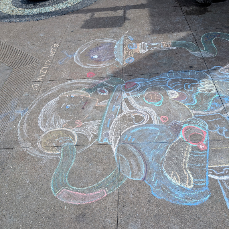 sidewalk chalk art: helmet of swordswoman in mechanized armor with a pufferfish sidekick