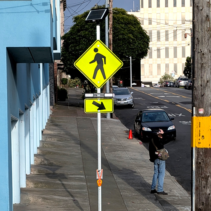 shiny new signpost with not-yet-operational pushbutton hooked up to flashing lights by a Ped Xing sign with solar collector on top. not shown: the little cannisters holding bright flags which people carried across Hillway hoping that drivers would notice them. SFMTA was very quick to take down this guerilla safety equipment, though it's taking them several days to install the official stuff