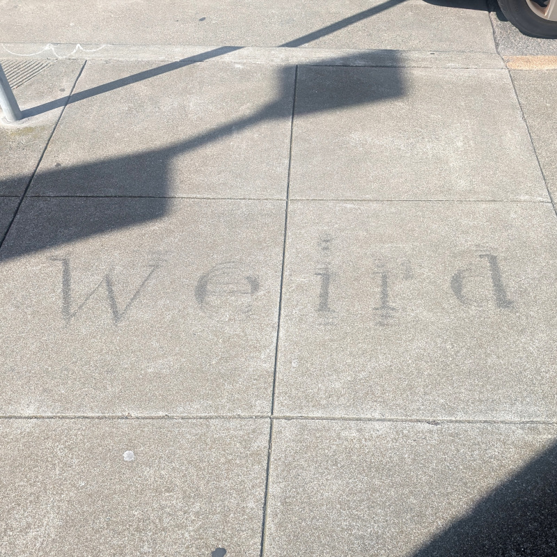 sidewalk graffito: 'weird' but blurry