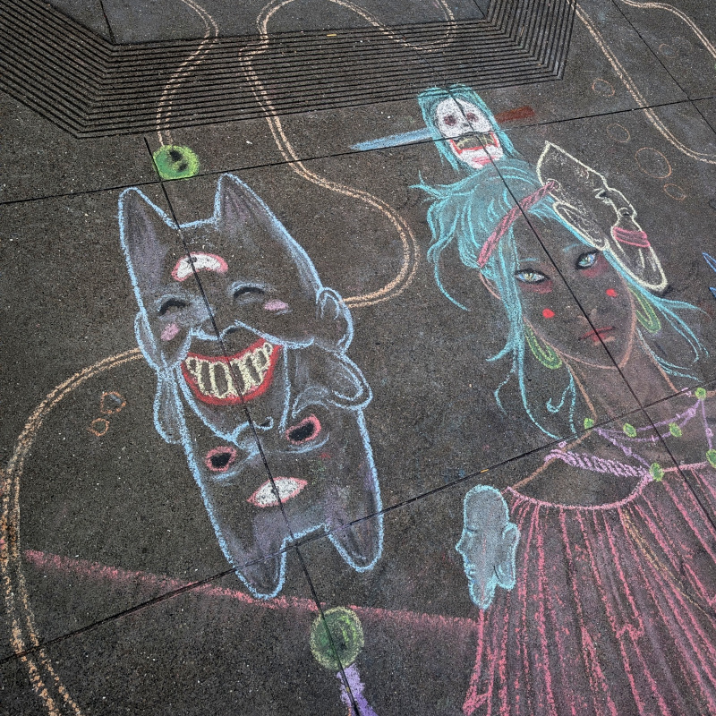 sidewalk chalk art. upper left of the artwork. view of one of the masks plus the figure's head. She wears her head in a bun held together with a knife through a skull. She wears a mask, but slung around the side of her head, not covering her face at the moment. The mask isn't, uh, semordnilap-ic; uh, i mean it isn't meant to be turned upside down