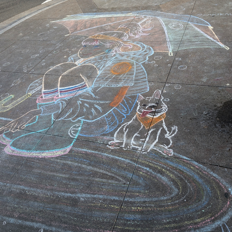 sidewalk chalk art: a lady crouches at the edge of a small pond. A puppy sits behind her